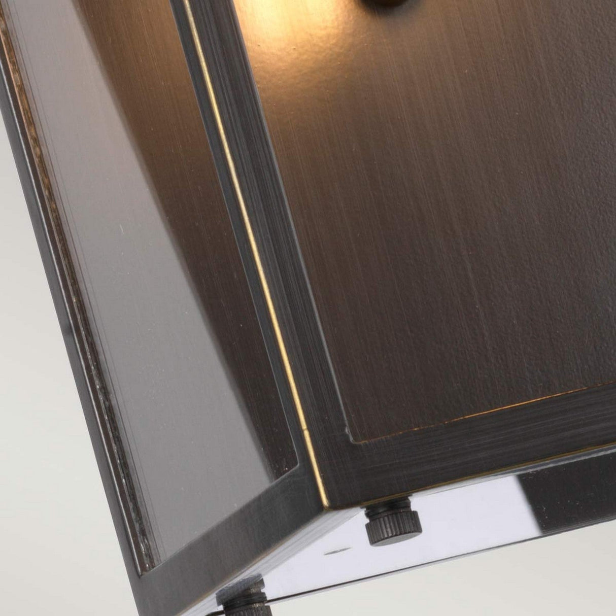 Close-up of the Glenview 1 Light Outdoor Medium Wall Lantern in antique bronze, showcasing a modern wall-mounted design with a sleek, rectangular form. Its smooth surface emits a warm, subtle glow from within, casting soft light along the edges that evoke prairie-style design elements.