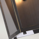 Close-up of the Glenview 1 Light Outdoor Medium Wall Lantern in antique bronze, showcasing a modern wall-mounted design with a sleek, rectangular form. Its smooth surface emits a warm, subtle glow from within, casting soft light along the edges that evoke prairie-style design elements.