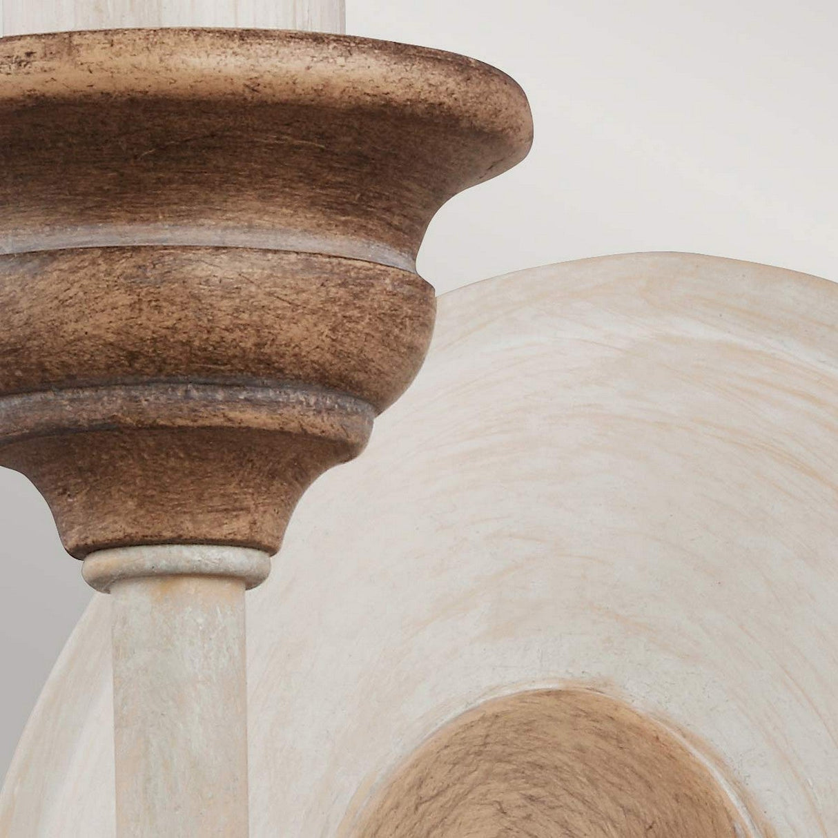 Close-up of the Hartsville 1 Light Wall Light featuring a circular carved detail in chalk washed and beachwood tones. The intricate design highlights the grain and texture, showcasing its rustic charm. Soft lighting enhances the smooth finish, adding to its elegant farmhouse style appearance.