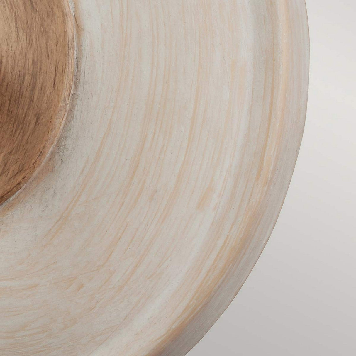 Close-up of the Hartsville 1 Light Wall Light, highlighting its abstract circular wooden pattern with layers of light brown and beige concentric rings resembling a tree trunk cross-section. The wood grain and texture, enhanced by a chalk-washed finish, exude rustic charm and create a natural, earthy aesthetic.
