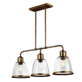 The Hobson 3 Light Island Light in Aged Brass showcases a contemporary design with three seeded glass dome shades, each gracefully enclosing an exposed bulb. This chic island light is suspended by two rods attached to a rectangular ceiling mount.