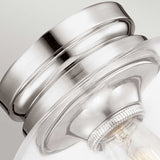 Close-up image of the Hounslow 1 Light Flush in a polished nickel finish. This elegantly designed ceiling light fixture features a curved shape and a clear glass shade that encases a light bulb, set against a neutral grey background.