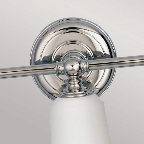 A close-up of the Huguenot Lake 3 Light Wall Light - Polished Chrome highlights its elegant design with a polished circular backplate and horizontal rod. It boasts a white conical glass shade, offering a modern and sleek look that epitomizes contemporary style.