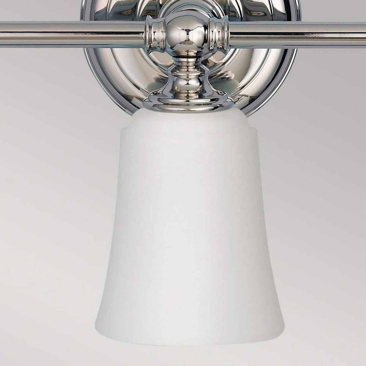 Introducing the Huguenot Lake 3 Light Wall Light in Polished Chrome, featuring a modern design with a sleek chrome base and frosted white glass shades. The fixtures hang downward from their metallic supports, creating a minimalist aesthetic that perfectly complements neutral backdrops and embodies the essence of contemporary wall lighting.