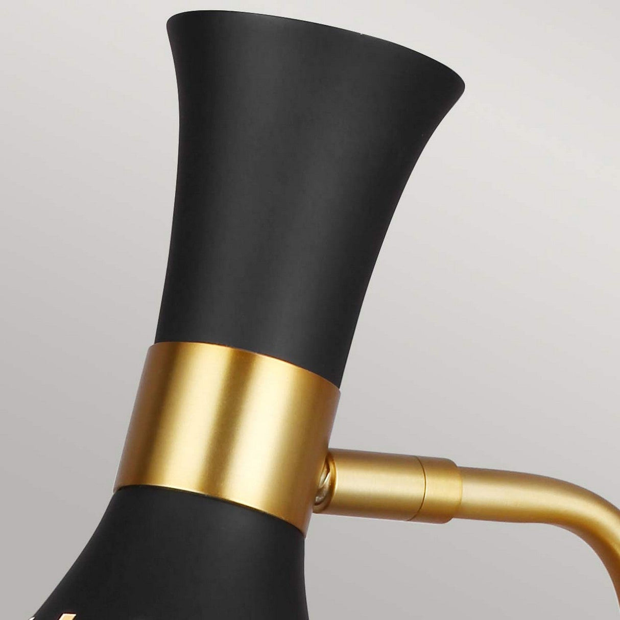 Close-up of the Joan 1 Light Table Lamp, showcasing a midnight black flared shade and a burnished brass cylindrical accent. This fixture offers a sleek, minimalist design with a metallic arm connecting to the cone-shaped shade.