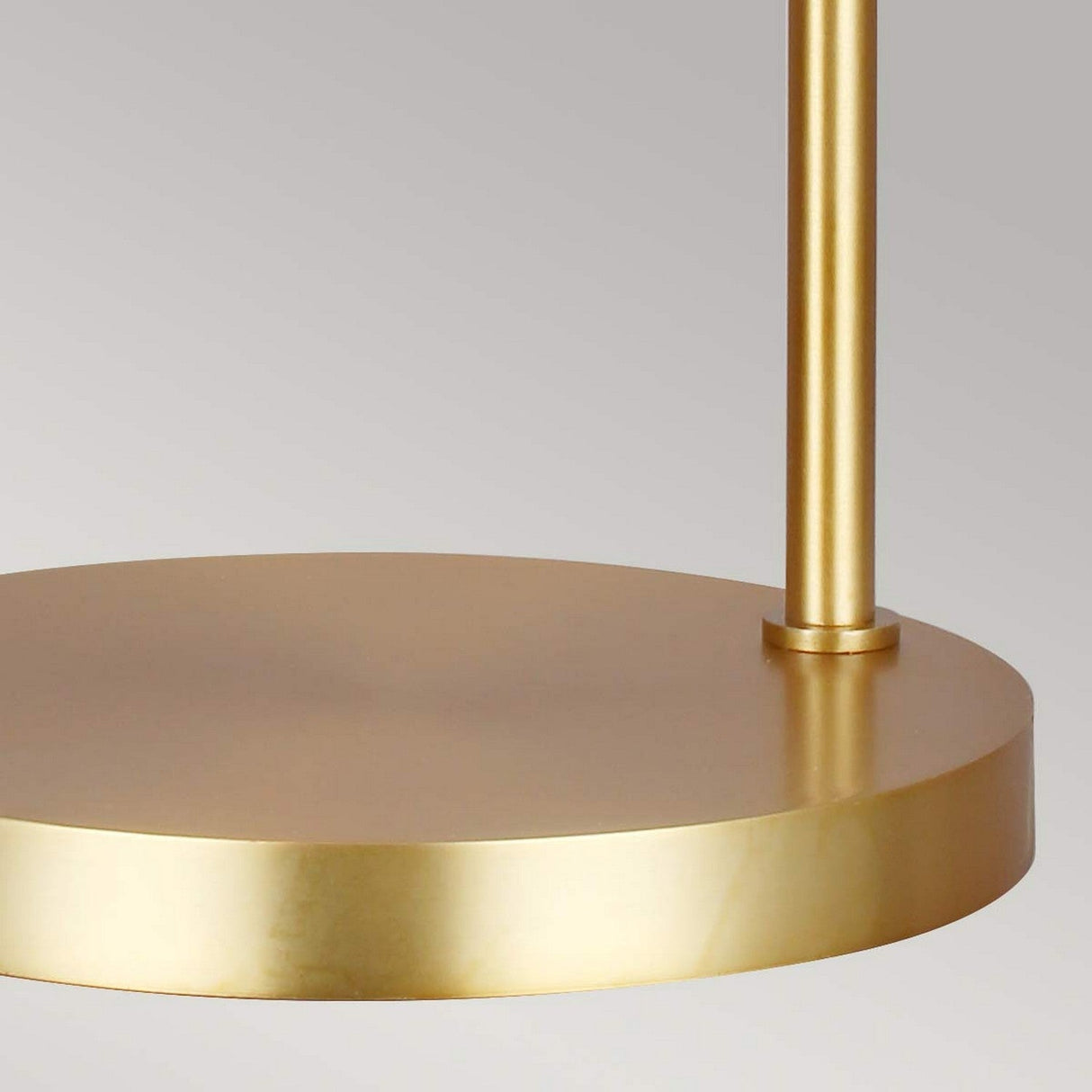 Close-up of the Joan 1 Light Table Lamp in Midnight Black and Burnished Brass, featuring a cylindrical base and a round, flat top. Its surface boasts a smooth, shiny finish that subtly reflects light. The neutral gray background accentuates the lamp's sleek, modern design.
