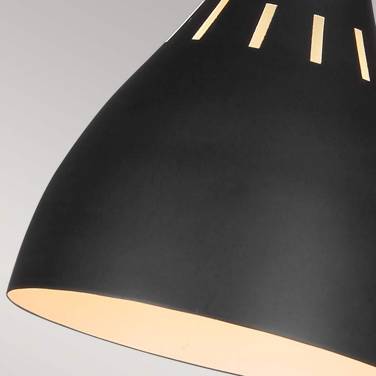 Close-up of the Joan 1 Light Table Lamp in Midnight Black and Burnished Brass, showcasing narrow slits near the top that let light shine through. The interior is illuminated, casting a warm glow against a plain gray background, adding an elegant touch to any space.