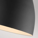 Close-up of the Joan 1 Light Wall Light in Midnight Black/Burnished Brass against a light gray background. The partially visible shade softly emits light from within, enhancing the modern design with a touch of elegance.