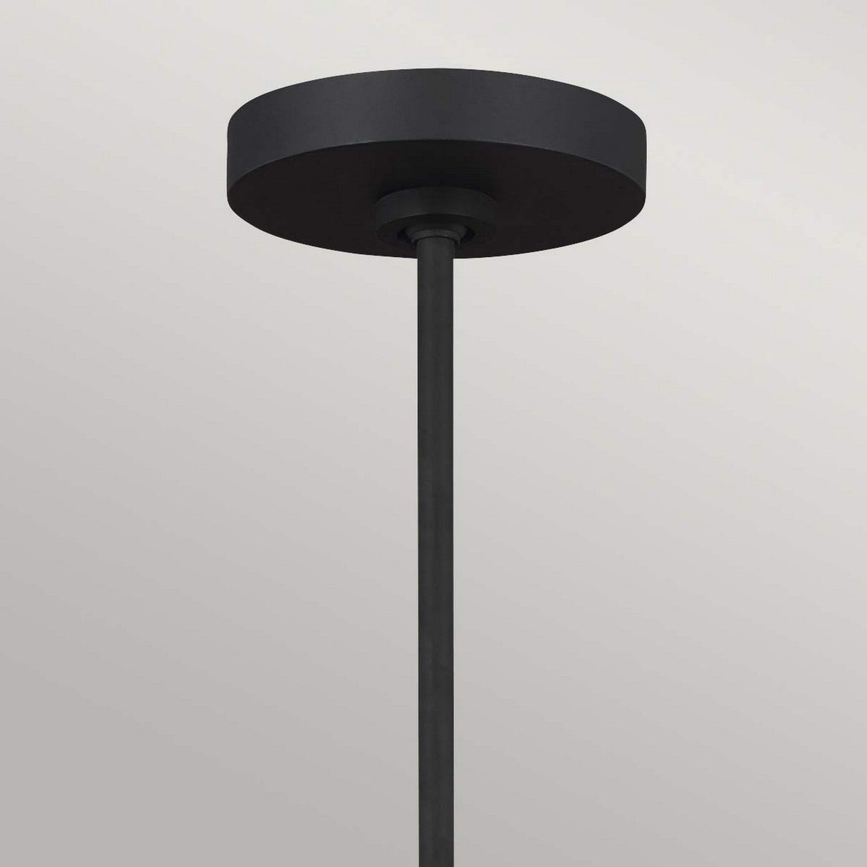 A minimalist Joan 5 Light Chandelier in midnight black and burnished brass showcases a cylindrical base and a long vertical rod, set elegantly against a light gray background.