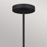 A minimalist Joan 5 Light Chandelier in midnight black and burnished brass showcases a cylindrical base and a long vertical rod, set elegantly against a light gray background.