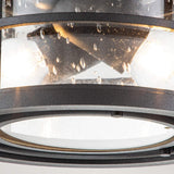A detailed view of the Lighthouse 2 Light Outdoor Flush - Textured Black reveals a solid brass cage surrounding the fixture. The glass, with its raindrop texture, perfectly accentuates the textured black finish while housing two bulbs that emit a warm glow, adding an aesthetic touch to its design.