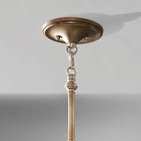 Close-up of a ceiling-mounted metallic light fixture, showcasing a circular base connected by a chain. The fixture resembles the Lucia 3 Light Chandelier - Burnished Silver and hangs from the ceiling against a light gray background.