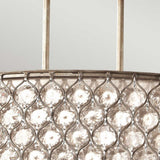 Close-up of the Lucia 3 Light Large Chandelier - Burnished Silver, showcasing a metallic frame with a repeating diamond pattern that encloses Bauhinia crystals. These crystals amplify the light, enhancing the chandelier's ornate design against a soft gray backdrop.