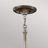 The Lucia 6 Light Chandelier in burnished silver showcases a close-up of its ceiling mount, featuring a round canopy and hanging rod linked by chain links. Its elegant hardware is set against a light gray background, imparting a vintage aesthetic.