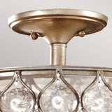 Close-up of the Lucia 1 Light Semi Flush with an elaborate burnished silver finish and Bauhinia Crystals. The fixture showcases a circular design adorned with clear, round crystal accents suspended in a pattern around the frame, beautifully reflecting light. The backdrop is a plain, light-colored wall.