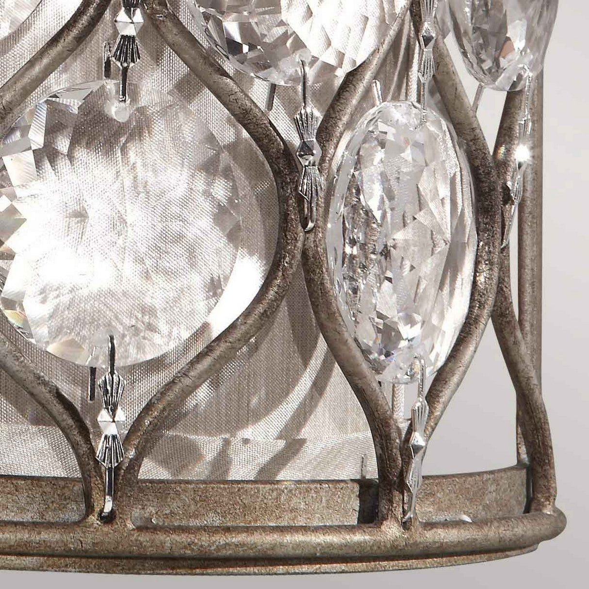 A close-up of the Lucia 1 Light Wall Light showcases its burnished silver metal frame adorned with large, oval Bauhinia crystals that beautifully reflect light. The intricate design creates a shimmering effect, accentuating the brilliance of the crystals.