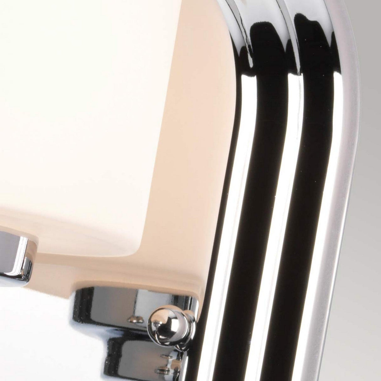 A close-up of the Malibu 1 Light Wall Light showcases its polished chrome frame and opal-etched glass shade. The lamp's sleek and minimalist design stands out against a neutral gray background.
