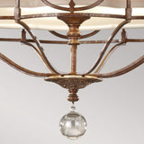 Close-up of the Marcella 3 Light Chandelier in bronze, featuring an intricate filigree design and a spherical glass pendant light that offers ambient illumination. Its curved arms and soft beige shade stand elegantly against a plain light gray background.
