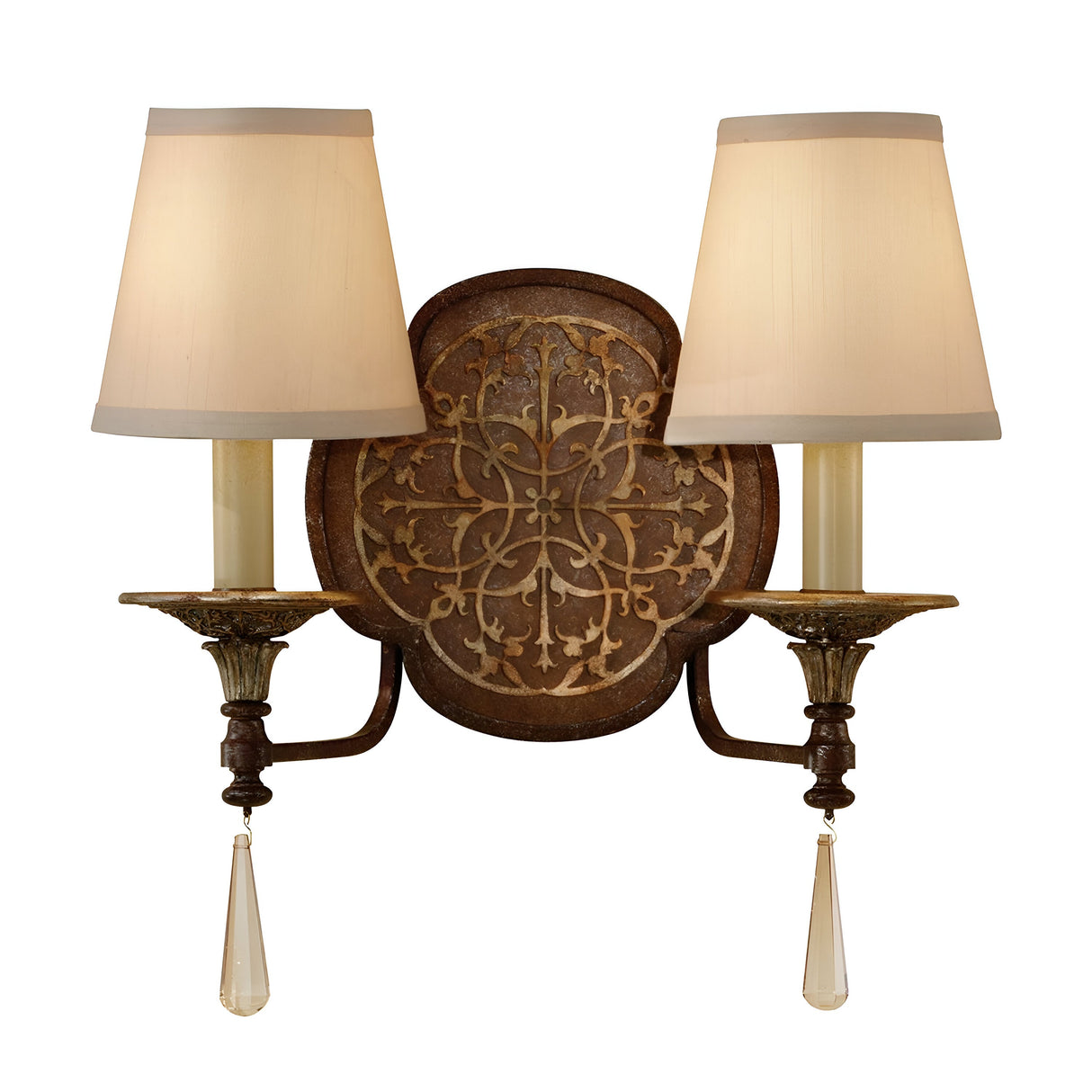 The Marcella 2 Light Wall Light - Bronze is a vintage piece ideal for luxury home decor. It features two beige lampshades, an ornate circular metal backplate with intricate vine patterns, and candle-like arms adorned with hanging crystal-like decorative pieces and exquisite filigree detailing.