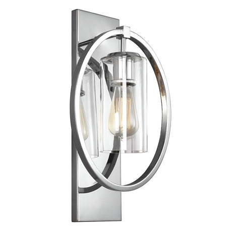 The Marlena 1 Light Wall Light in polished chrome is a wall-mounted modern fixture with a cylindrical glass shade surrounded by a circular chrome frame. It features a sleek, geometric design with a reflective surface that showcases the visible filament bulb inside.