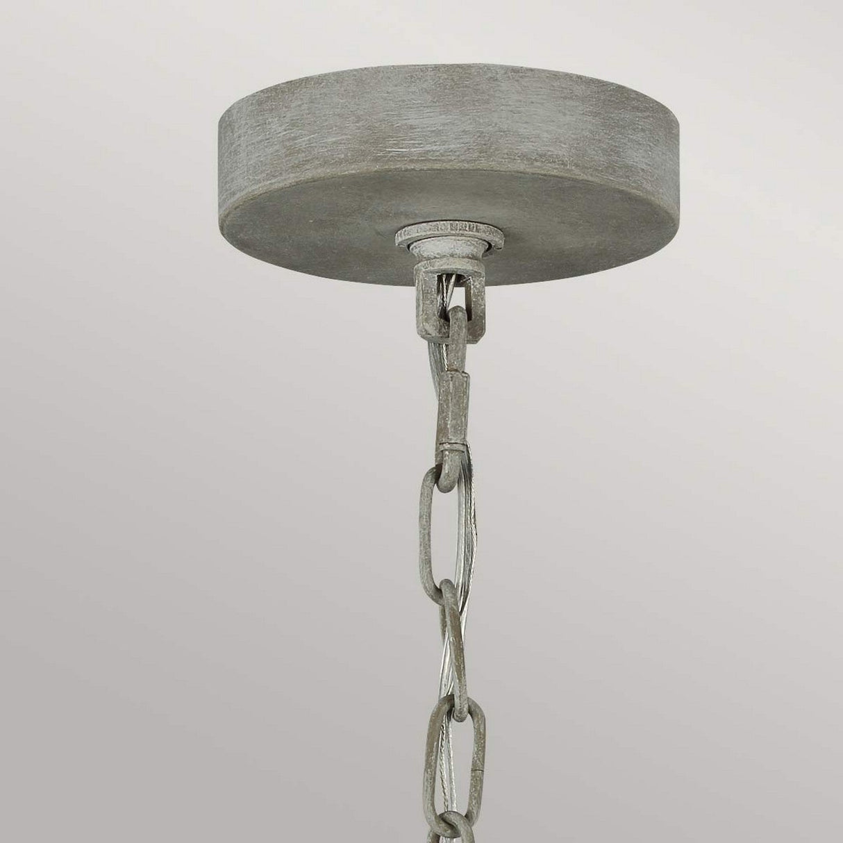 A close-up of a ceiling light fixture with a metallic, circular canopy and a chain hanging from it exudes rustic charm. This Maryville 9 Light Chandelier - Washed Grey stands out against a plain, light gray background, effortlessly blending elegance with French Country sophistication.