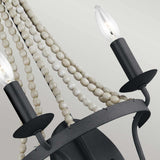 A detailed view of the Nori 2 Light Wall Light showcases its two candle-shaped bulbs elegantly perched on black metal arms. Delicate strands of white beads gracefully drape over a circular frame finished in dark weathered zinc with driftwood grey, contributing to an elegant vintage aesthetic infused with a hint of Gothic style.