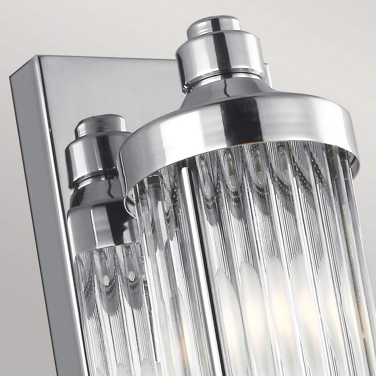 Close-up of the Paulson 4 Light Bar Light - Chrome, featuring modern chrome detailing and vertical glass tube shades. The fixture reflects light beautifully, creating a sleek and elegant look against a light gray background.