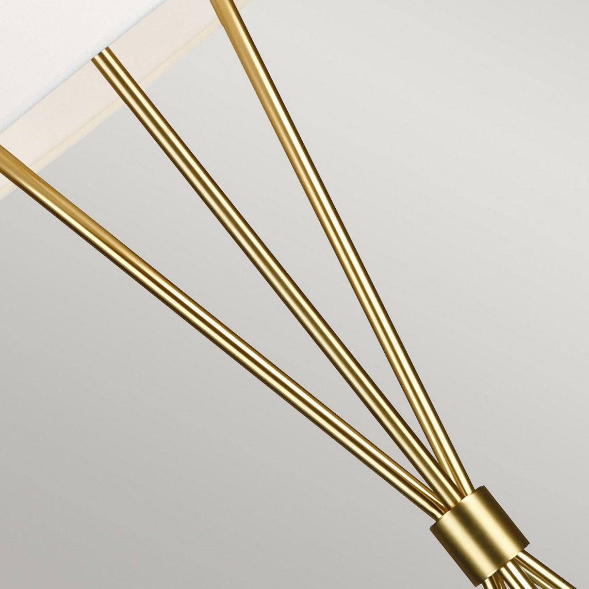 Featuring the Penny 1 Light Floor Lamp with a white shade and three burnished brass rods converging at the base, this close-up highlights its mid-century elegance against a soft gray background.