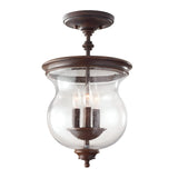 The Pickering Lane 3 Light Semi Flush - Bronze is a vintage-style ceiling light fixture that exudes rustic farmhouse charm. It features a beautiful bronze finish and three candle-like bulbs enclosed in a clear seeded glass dome, with elegant curves and a classic look enhancing its design.