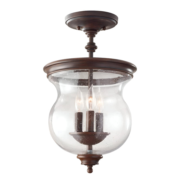 The Pickering Lane 3 Light Semi Flush - Bronze is a vintage-style ceiling light fixture that exudes rustic farmhouse charm. It features a beautiful bronze finish and three candle-like bulbs enclosed in a clear seeded glass dome, with elegant curves and a classic look enhancing its design.