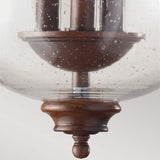 Close-up of the Pickering Lane 3 Light Semi Flush featuring a vintage-style design with a wooden base and clear, seeded glass shade. The speckled bubbles infuse rustic charm, while the bronze finish beautifully complements the candle-style bulbs visible through its enchanting globe.