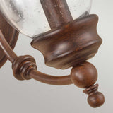 Featuring the Pickering Lane 2 Light Wall Light - Bronze, this rustic-style wall sconce displays a gracefully curved Heritage Bronze arm complemented by a decorative wooden accent and a clear glass shade. The smooth texture of the wood finish accentuates detailed craftsmanship against a light gray backdrop, imparting an elegant traditional aesthetic.