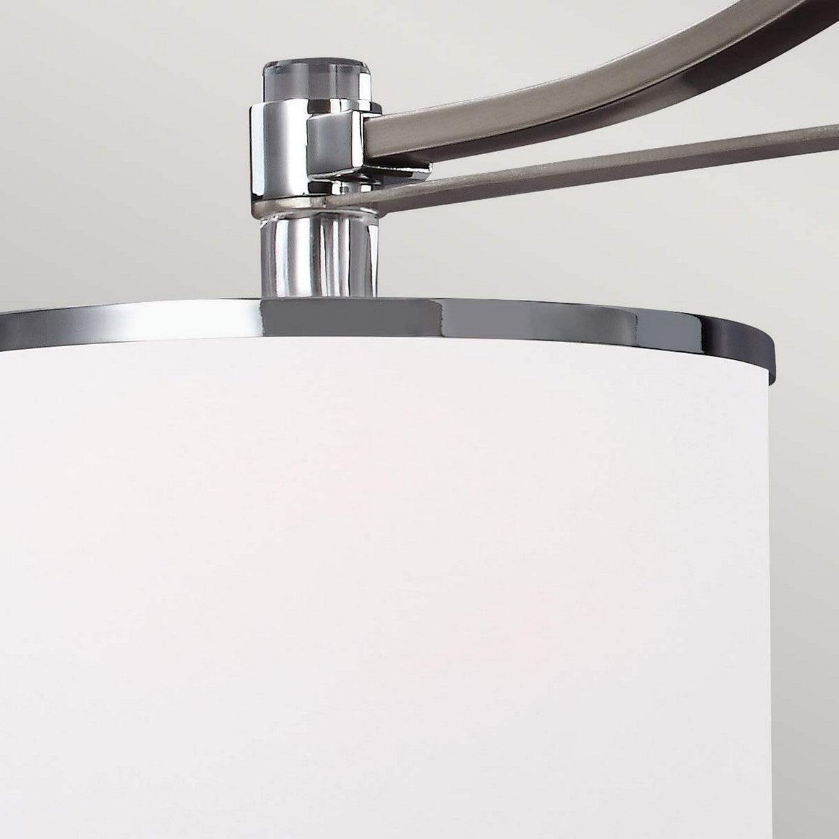 A close-up of the Prospect Park 3 Light Island Chandelier in satin nickel with chrome features a modern white cylindrical lamp shade with an arm fixture, accented by opal etched glass, set against a light gray background.