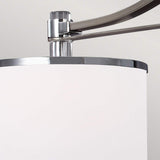 A close-up of the Prospect Park 3 Light Island Chandelier in satin nickel with chrome features a modern white cylindrical lamp shade with an arm fixture, accented by opal etched glass, set against a light gray background.