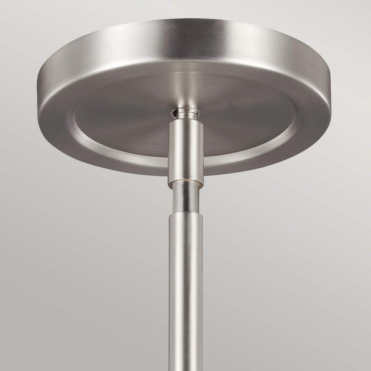 Close-up view of the Prospect Park 4 Light Chandelier in Satin Nickel with Chrome finish. The sleek design, resembling a minimalist chandelier, showcases a circular base and straight rod extending downward, set against a plain gray background. It can be paired with opal etched glass shades for added elegance in modern lighting.
