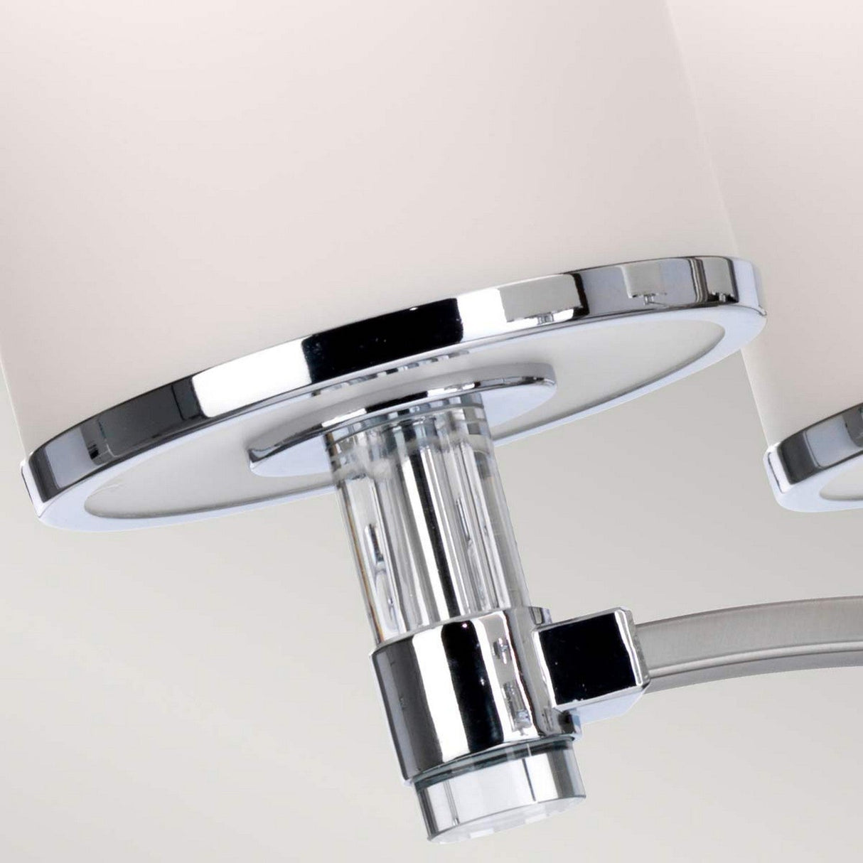 A detailed perspective of the Prospect Park 5 Light Chandelier in Satin Nickel with Chrome showcases its modern elegance. It features a cylindrical frosted glass shade, chrome accents, and a clear glass cylindrical connector that seamlessly integrates into transitional spaces with its sleek, contemporary design.