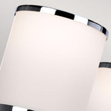 A close-up of sleek cylindrical light fixtures with chrome accents set against a neutral backdrop captures a modern elegance. The smooth lampshades softly diffuse light, evoking the gentle glow of the Prospect Park 5 Light Chandelier in Satin Nickel with Chrome.