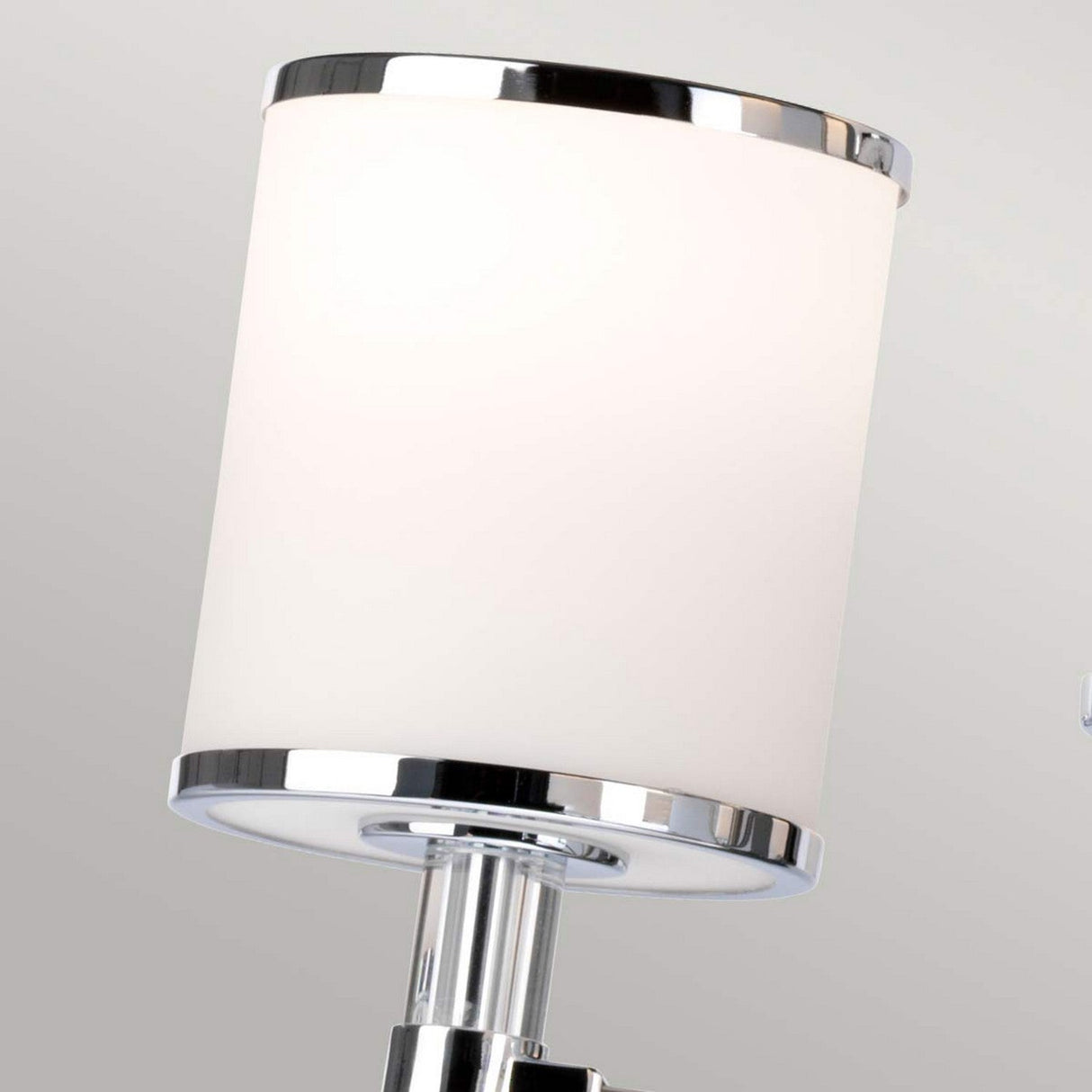 A modern wall lamp with a cylindrical opal etched glass shade and shiny chrome accents, set against a light gray background, reminiscent of the sleek and minimalist design of the Prospect Park 9 Light Chandelier - Satin Nickel With Chrome, wonderfully complements satin nickel fixtures.