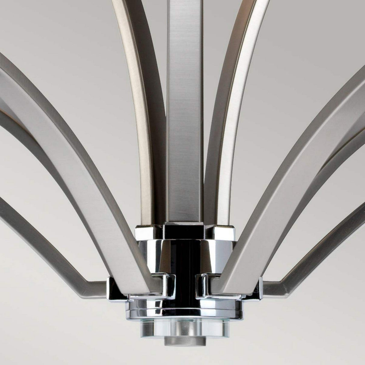 A close-up of the Prospect Park 9 Light Chandelier shows its metal arms radiating from a central hub, showcasing a modern satin nickel finish complemented by chrome accents. The elegantly curved arms are adorned with opal etched glass shades, forming a harmonious pattern against a neutral gray backdrop.