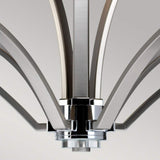 A close-up of the Prospect Park 9 Light Chandelier shows its metal arms radiating from a central hub, showcasing a modern satin nickel finish complemented by chrome accents. The elegantly curved arms are adorned with opal etched glass shades, forming a harmonious pattern against a neutral gray backdrop.