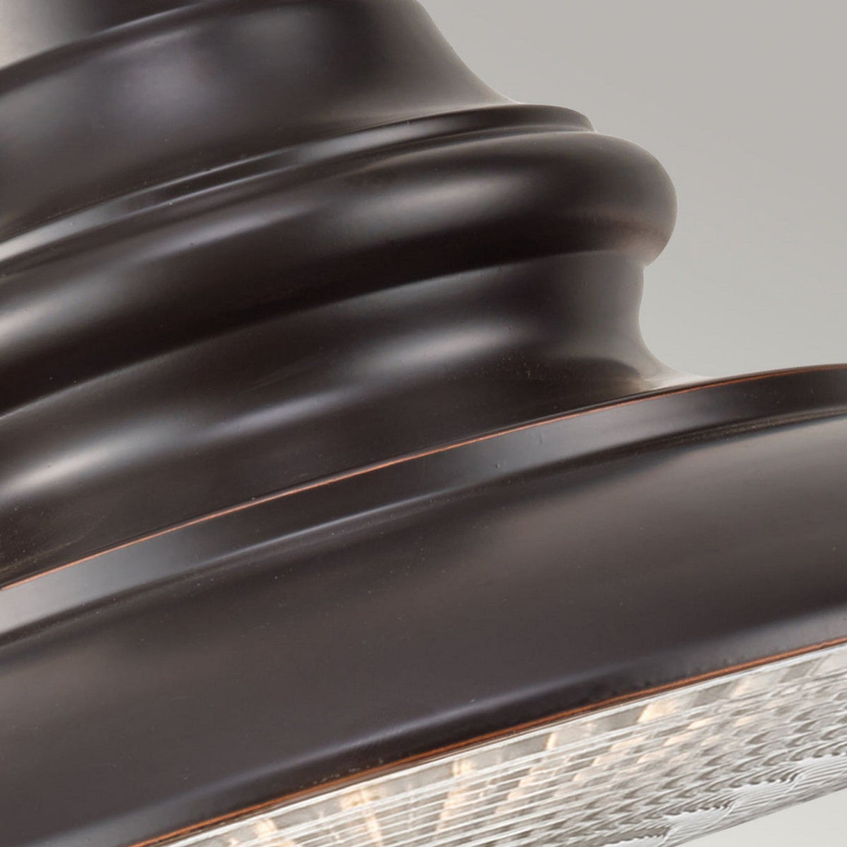 A close-up of the Redding Station 1 Light Outdoor Medium Chain Lantern in Dark Bronze reveals a rounded, layered design with a smooth and glossy metal surface. The lantern encases the bulb beneath textured glass, exuding elegance that enhances any sophisticated outdoor setting.