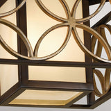 Close-up of the Remy 2 Light Flush - Heritage Bronze/Parissiene Gold, featuring a geometric design with overlapping circular metal patterns. The light emanating from within creates a warm, gentle glow that captures the spirit of French Arts and Crafts design.