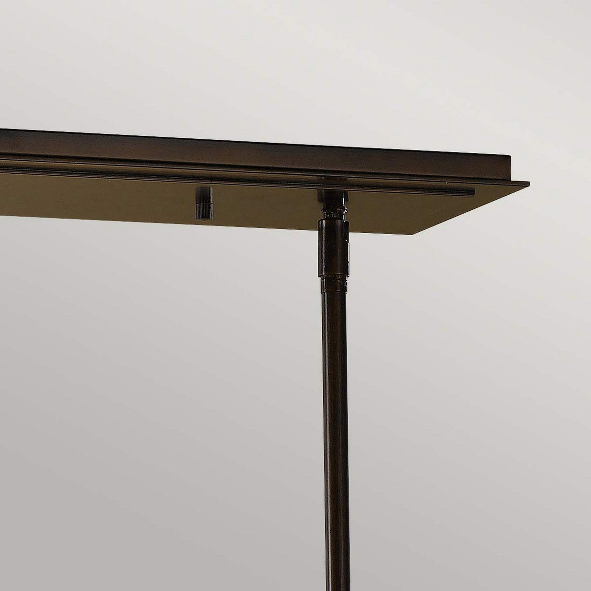 A close-up of the Remy 4 Light Pendant Chandelier showcases its dark metal structure, enhanced by a Parisienne Gold finish. The minimalist design, featuring clean lines and a modern aesthetic, stands out beautifully against a neutral background.