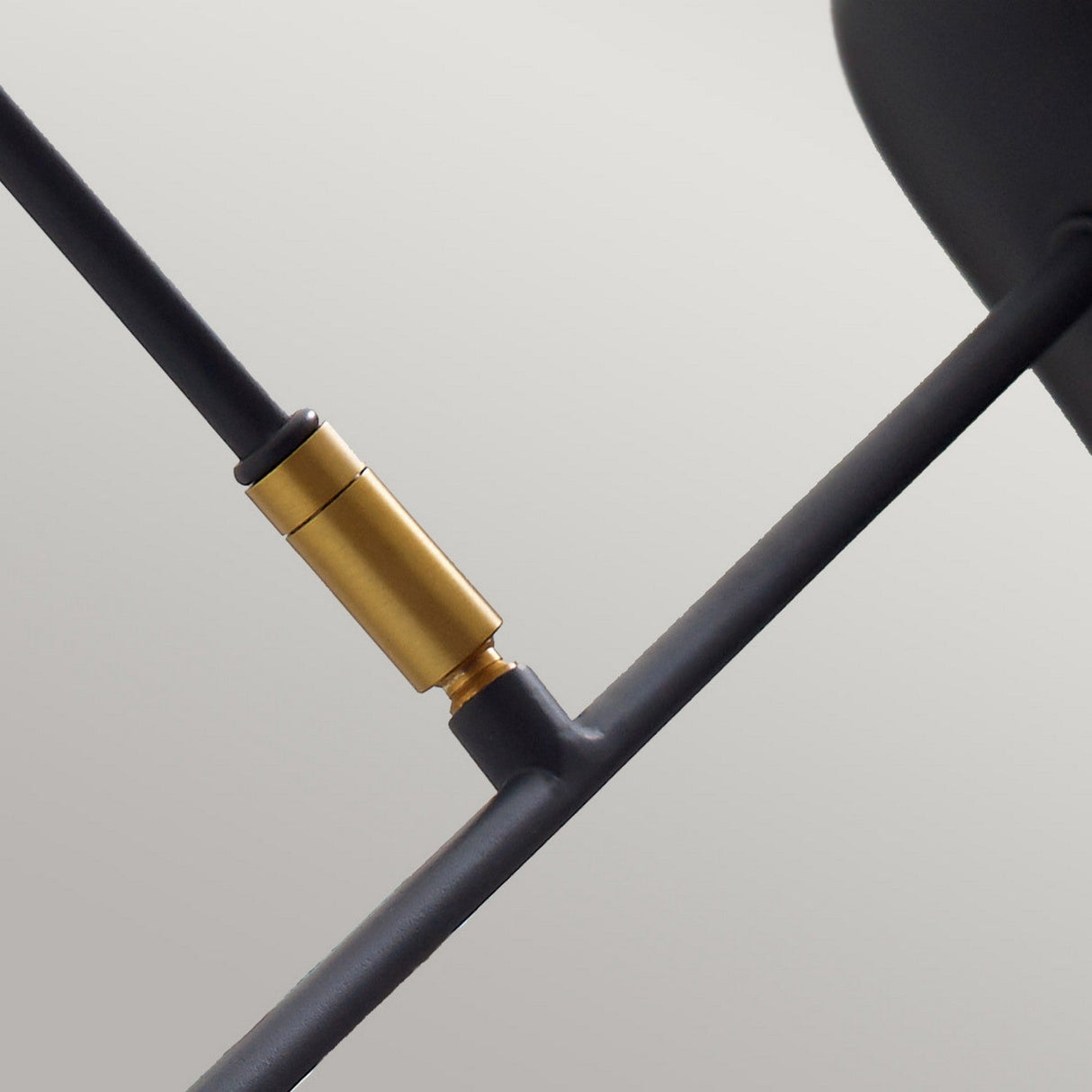 Featuring the Simon 1 Light Wall Light - Black, this image highlights its sleek black metal rods with a Midnight Black finish. The adjustable arm connects through a gold cylindrical joint against a light gray background.