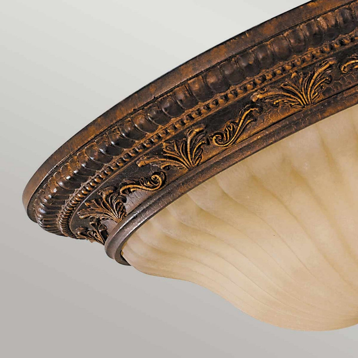 A close-up of the Sonoma Valley 2 Light Flush, showcasing its antique bronze finish. This French Country Style fixture highlights intricate leaf patterns along the rim and a frosted glass shade with a curved, ribbed texture.