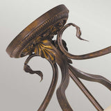 A close-up of the Sonoma Valley 3 Light Semi Flush - Cream/Bronze reveals an ornate, vintage-style metal table base with intricate leaf patterns and curved legs, reminiscent of French Country antiques, and boasts a distressed bronze finish.