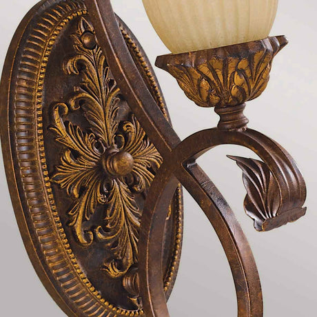 A detailed view of the Sonoma Valley 1 Light Wall Light in cream and bronze showcases its intricate floral and leaf patterns reminiscent of French country antiques. The curved arm supports a frosted glass fixture, adding an ornate touch perfect for charming Sonoma Valley homes.