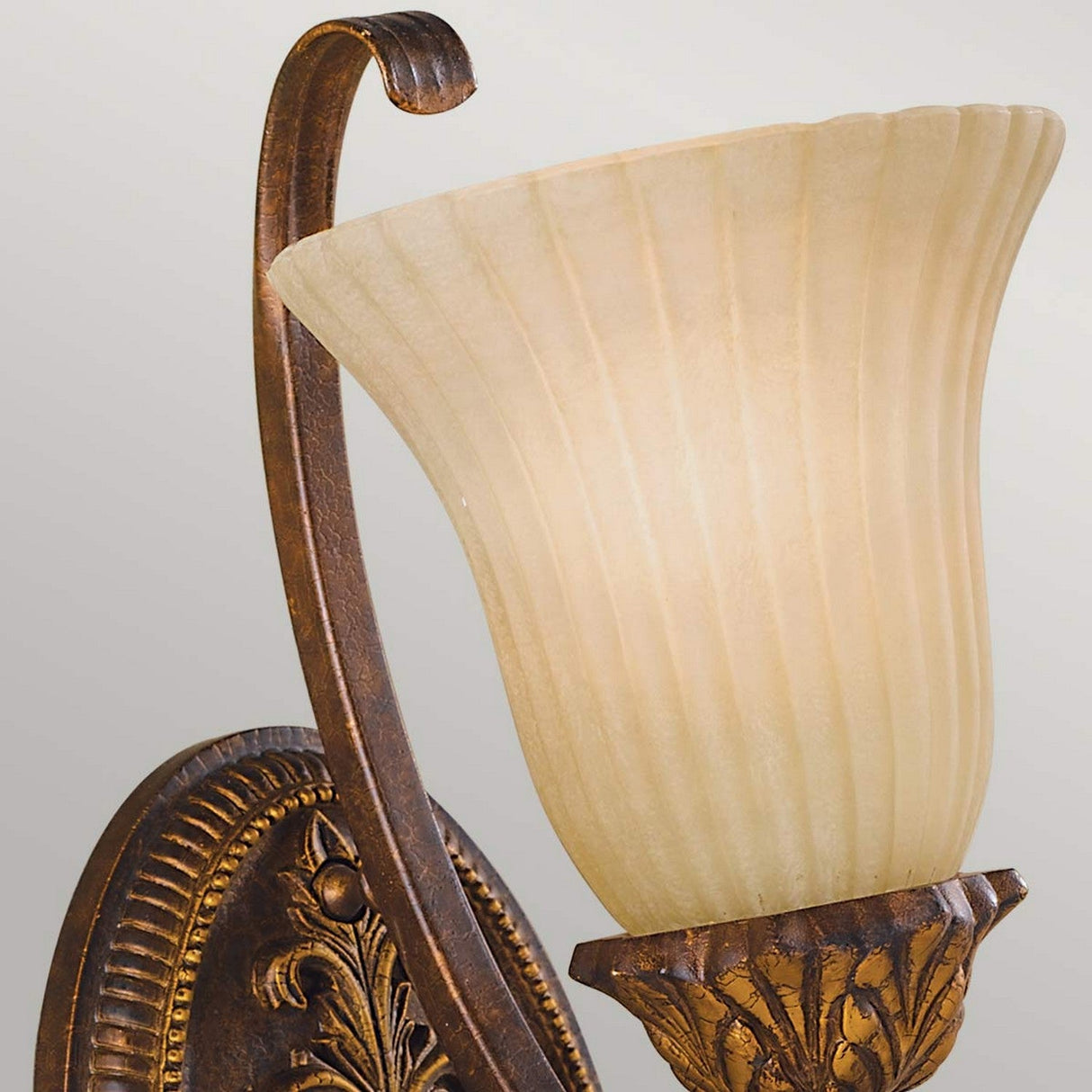 The Sonoma Valley 1 Light Wall Light in Cream/Bronze features an ornate bronze finish with a frosted glass lampshade in a fluted design. Reminiscent of French country antiques, its elegant bracket is intricately detailed for a classic look.