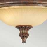 The Stirling Castle 2 Light Flush in bronze features an ornate design with a frosted, patterned glass shade reminiscent of Gothic arch motifs and a decorative finial. This fixture showcases intricate detailing for a classic, antique appearance.