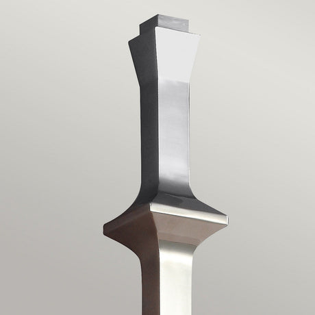 A tall, contemporary sculpture crafted with sleek, angular design elements and a smooth polished surface reminiscent of the Teva 1 Light Wall Light - Polished Nickel stands against a plain background. Its geometric contours and reflective shine embody a modern aesthetic, suggesting a contemporary art style.